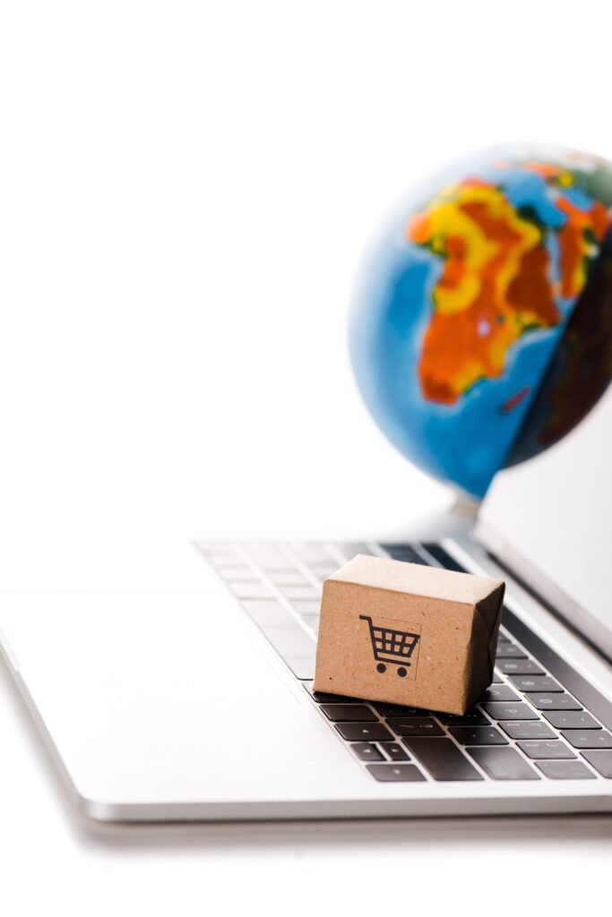 selective focus of toy carton box on laptop keyboard near globe isolated on white, e-commerce